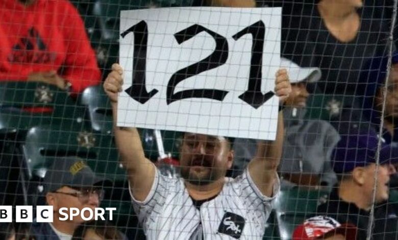 A fan holds up a '121' sign to mark the Chicago White Sox's record defeat